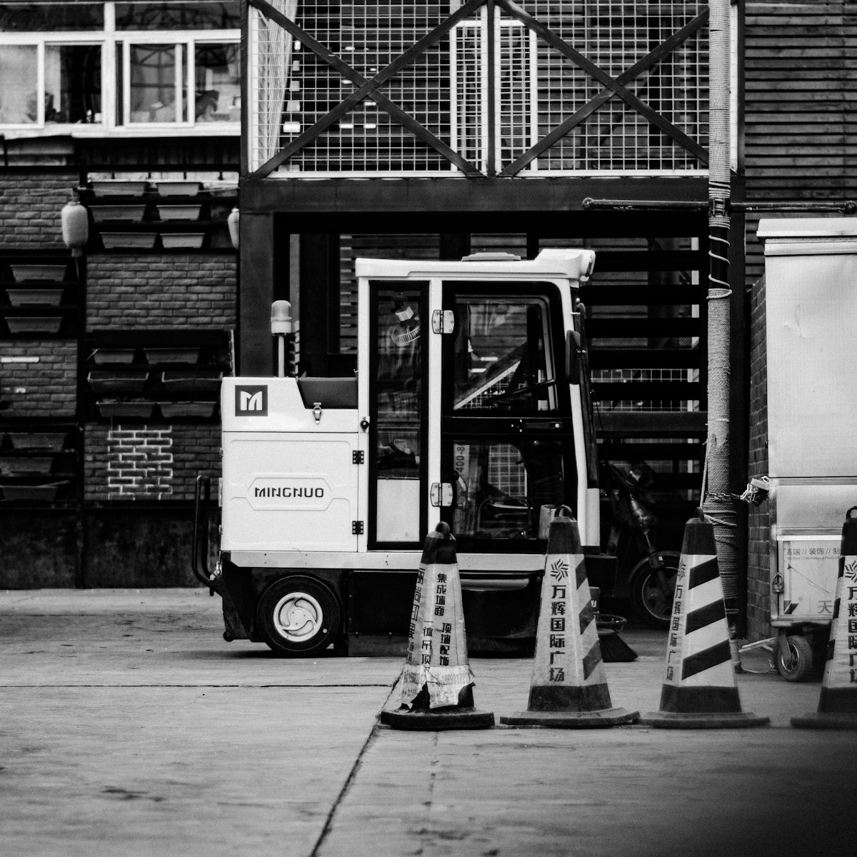 grayscale photo of man in black jacket and pants standing near white truck