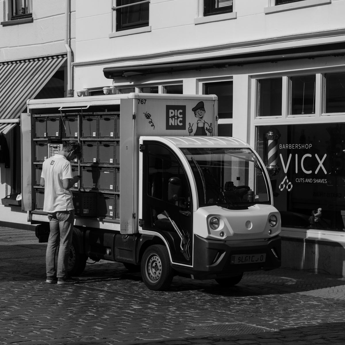 A black and white photo of a man standing next to a truck